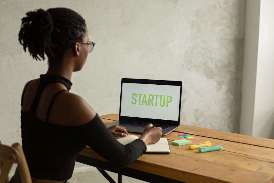 Back view of anonymous young African American businesswoman with bare shoulder and eyeglasses sitting at table with netb